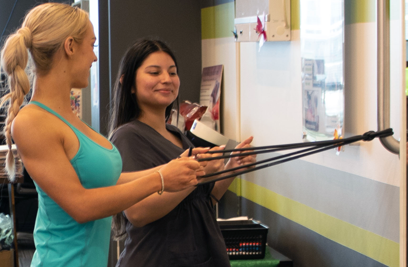 A patient performs active rehabilitative therapy with resistance bands under the supervision of a Chiro One team member to build strength and support recovery.
