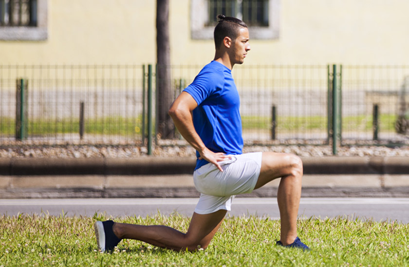 A man performing hamstring stretch outdoors to alleviate shooting leg pain and improve sciatic nerve mobility.