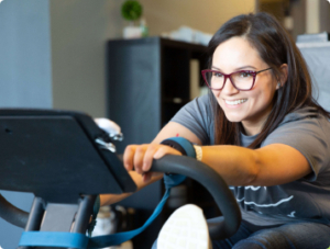 A smiling woman performs a rehabilitative stretching therapy inside a Chiro One chiropractic clinic