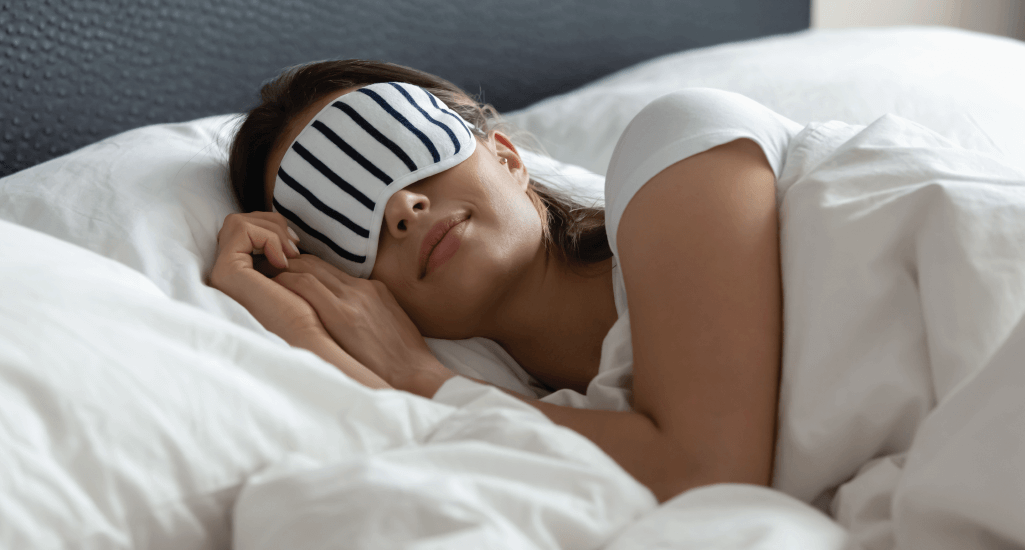 Woman sleeping in bed with sleep mask