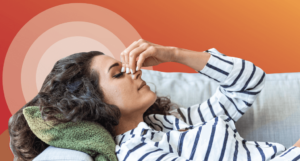 Woman in pain clutching upper nose on couch