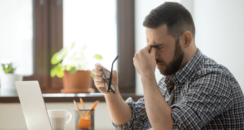 Man using a laptop with a headache