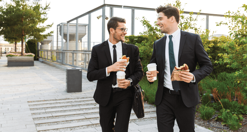 Two coworkers enjoying lunch together while taking a walk during their break
