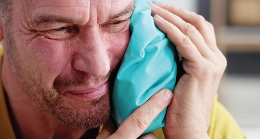 Male using a cold pack on hos jaw for pain