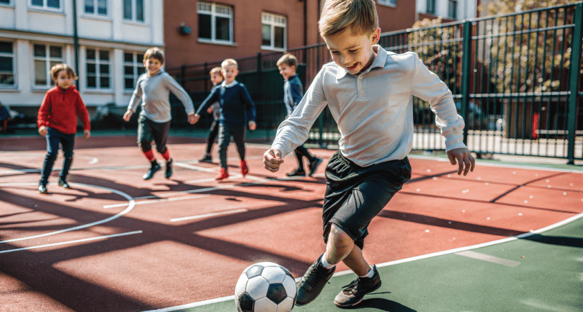Young boys playing soccer on the playground during school break.