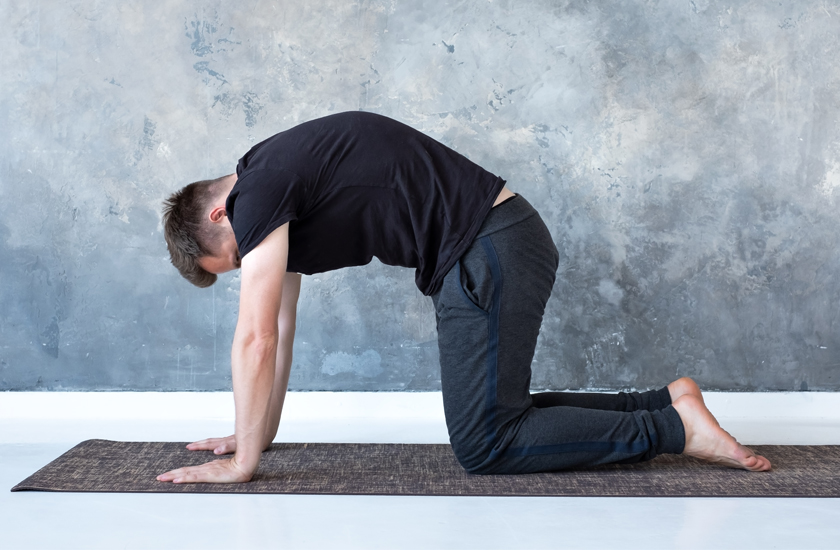 Man on floor mat in cat-cow position