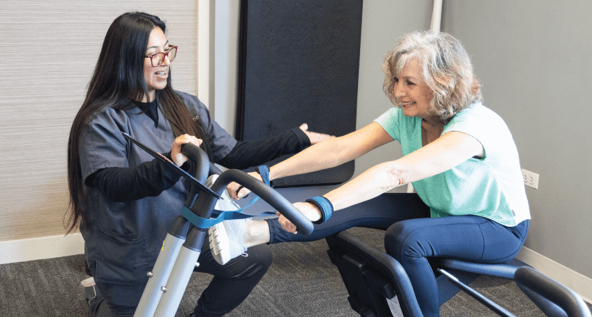 A woman receiving personalized chiropractic rehabilitation at Chiro One Clinic, using a specialized stretching machine guided by a professional clinician to improve joint mobility.
