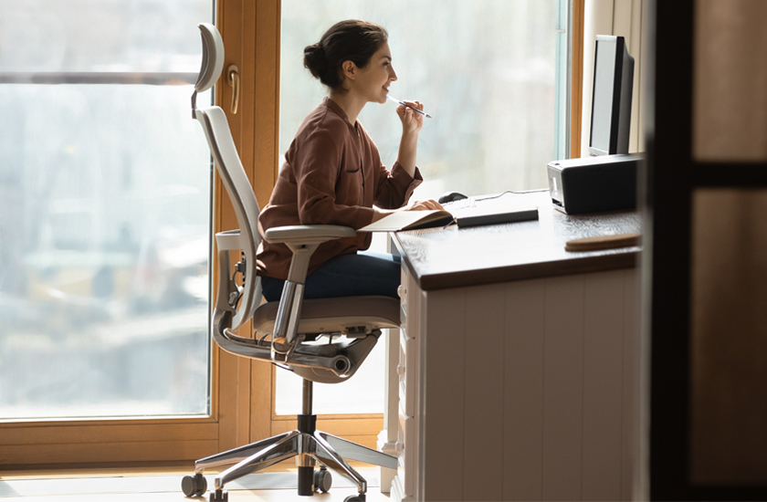 Woman working at a computer with a forward-leaning posture, a common habit that leads to spinal misalignment in professionals.