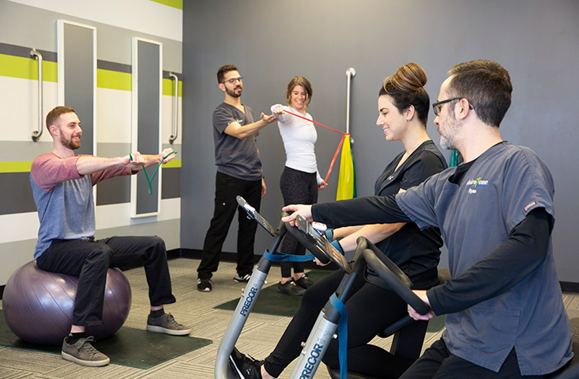 Patients and therapists at a Chiro One Clinic performing active therapy exercises to treat lower back pain.