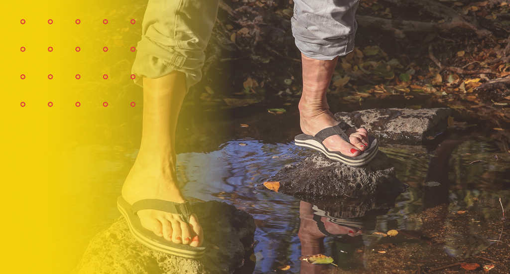 erson standing in water wearing flip-flops, illustrating how unsupportive footwear can impact posture and cause back pain.